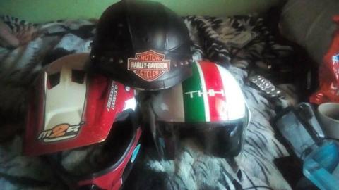 Three helmets and two pairs of googles.1 red, White,green road